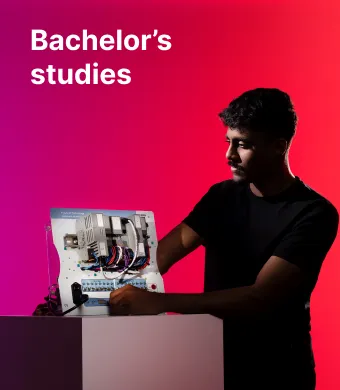 A young international student working with an electrical or engineering control panel against a bright pink and red background. The text in the upper left corner reads “Bachelor’s studies”.